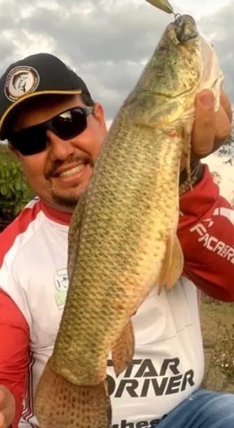 Pescador sorridente com peixe grande na Vila Quatro Estações