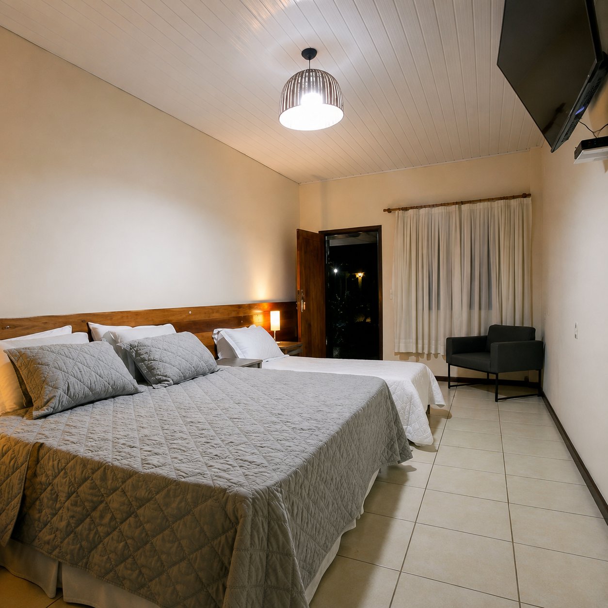Quarto com cama de casal, teto de madeira e TV
