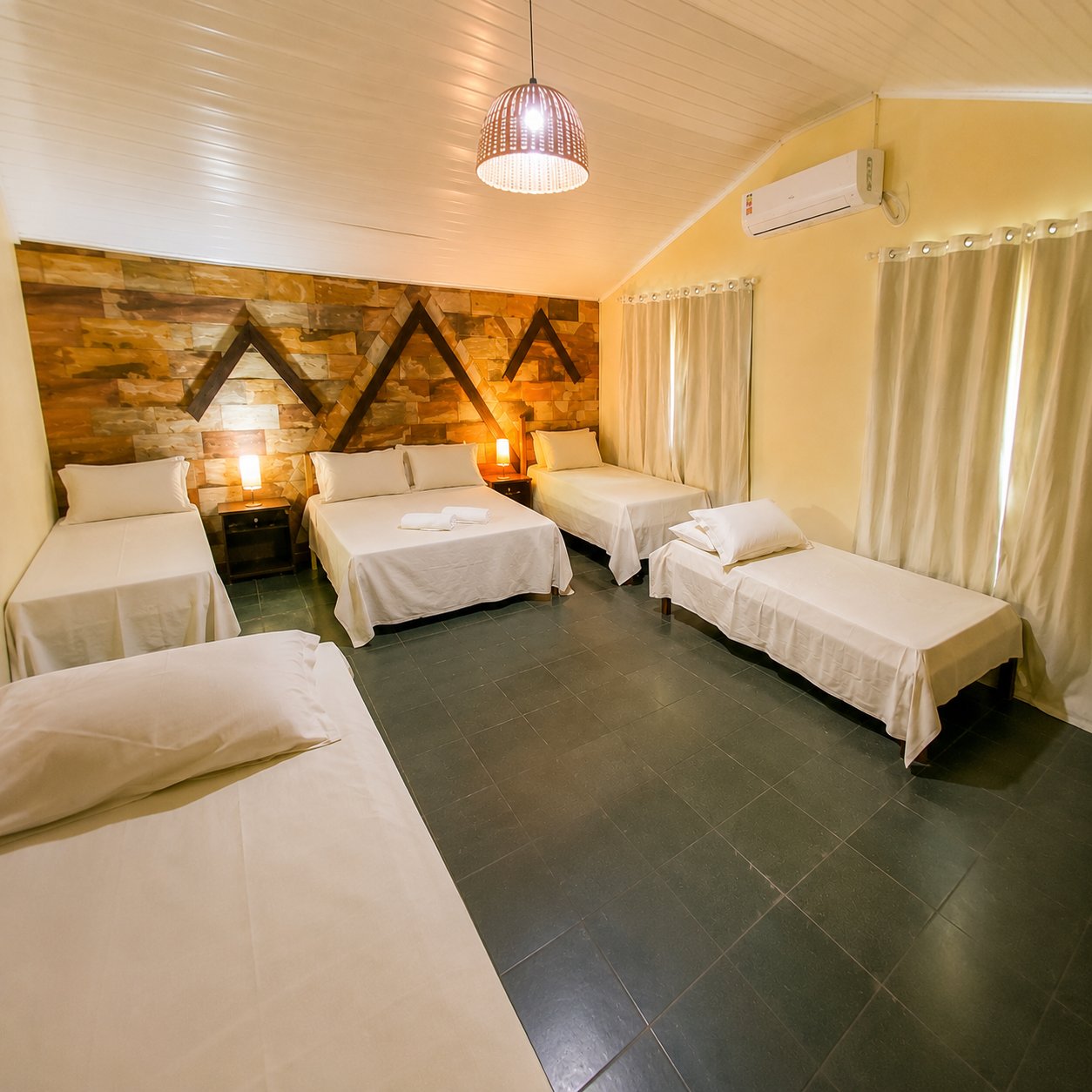 Quarto com parede rústica e quatro camas