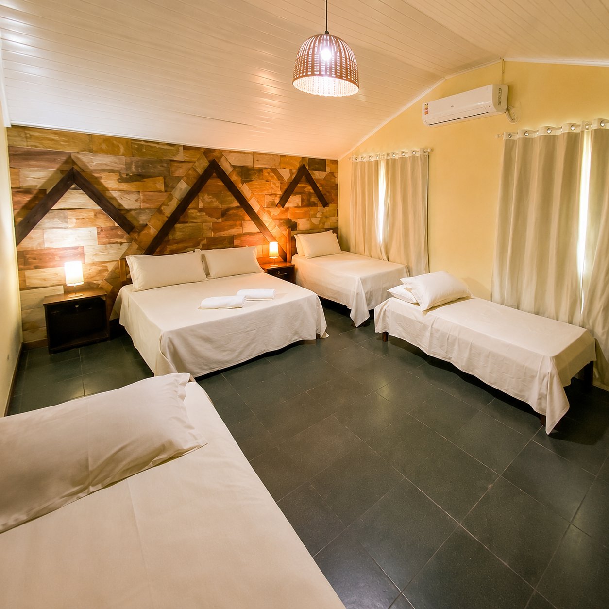 Quarto com parede rústica e camas de solteiro