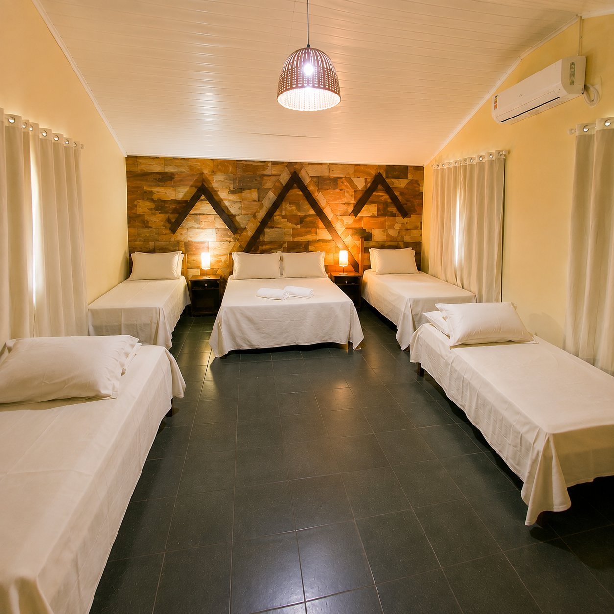 Quarto com parede rústica, vista ampla das camas